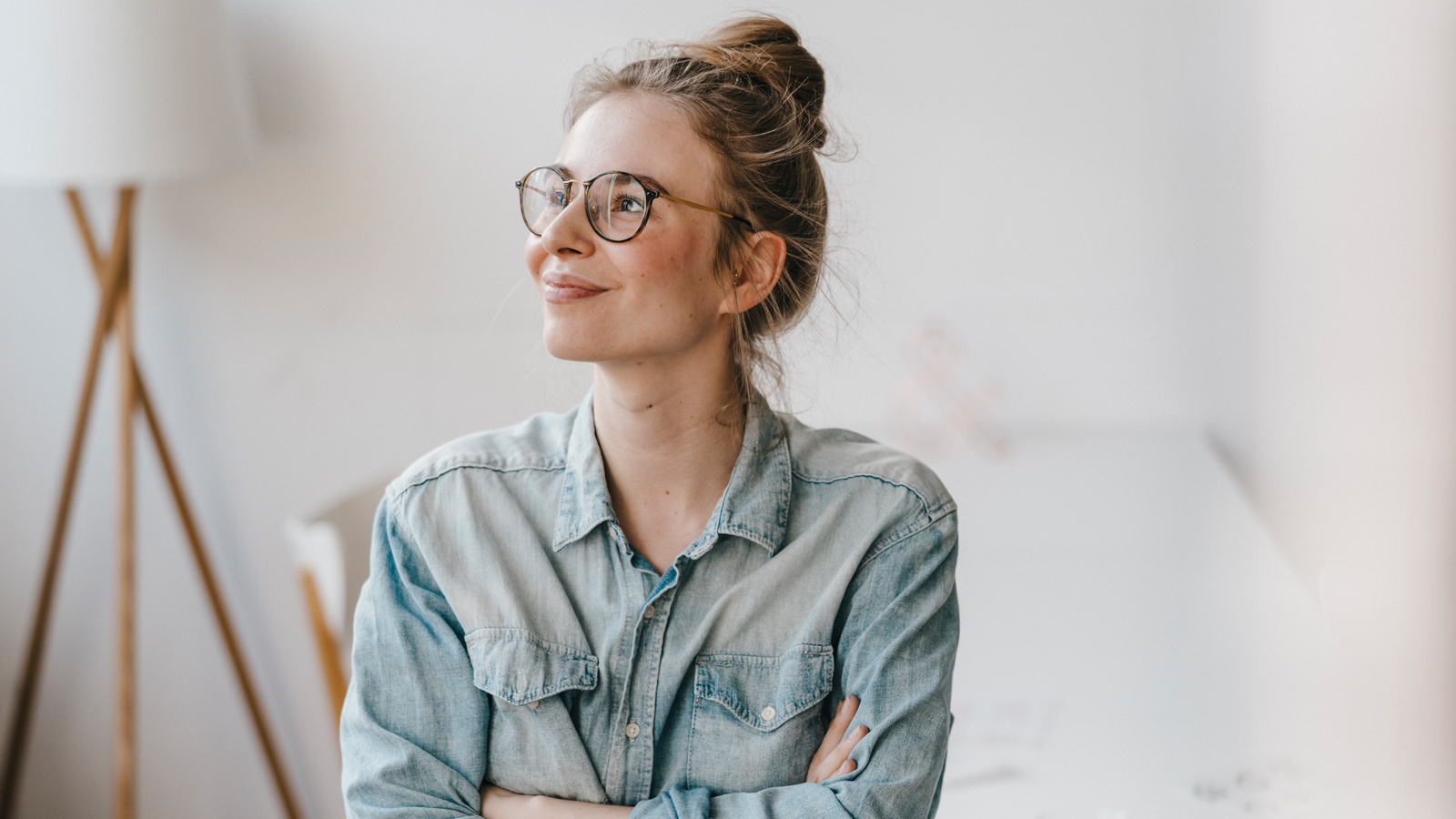 Eine Frau mit Hemd und Brille lächelt und freut sich über die Leistungen ihrer Krankenkasse für die Brille.