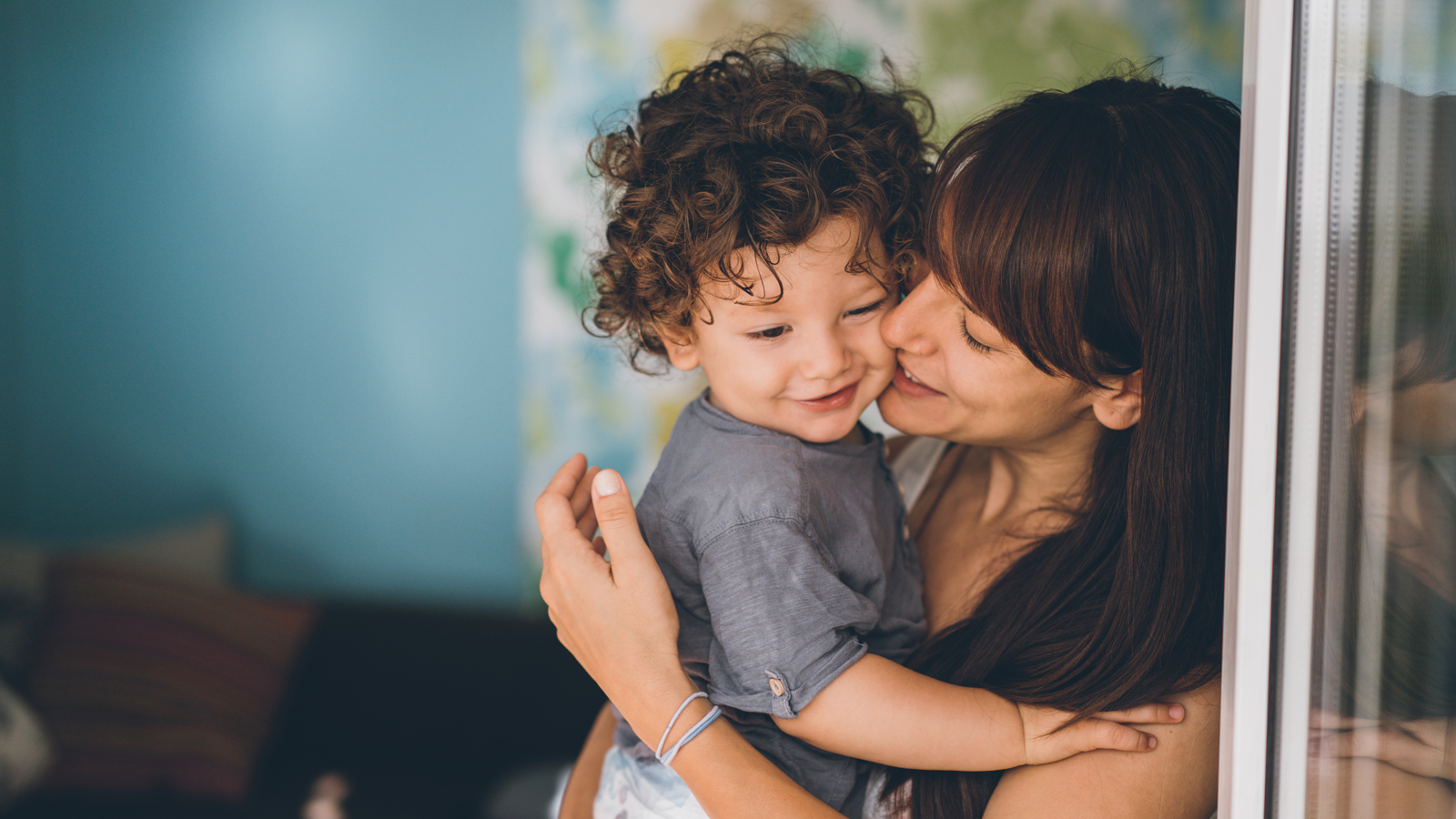 A young smiling mother holds a child, thankful for the complete cover provided by the supplementary health insurance for children.